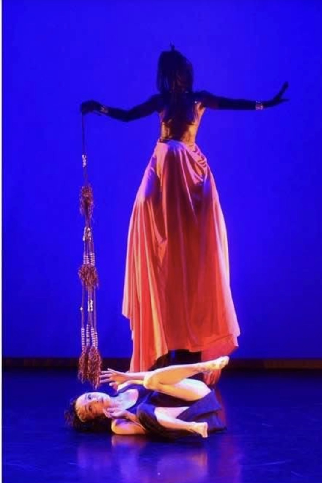 Scène de Né au mauvais endroit, au mauvais moment, dans le mauvais corps : deux danseuses sous une lumière bleue